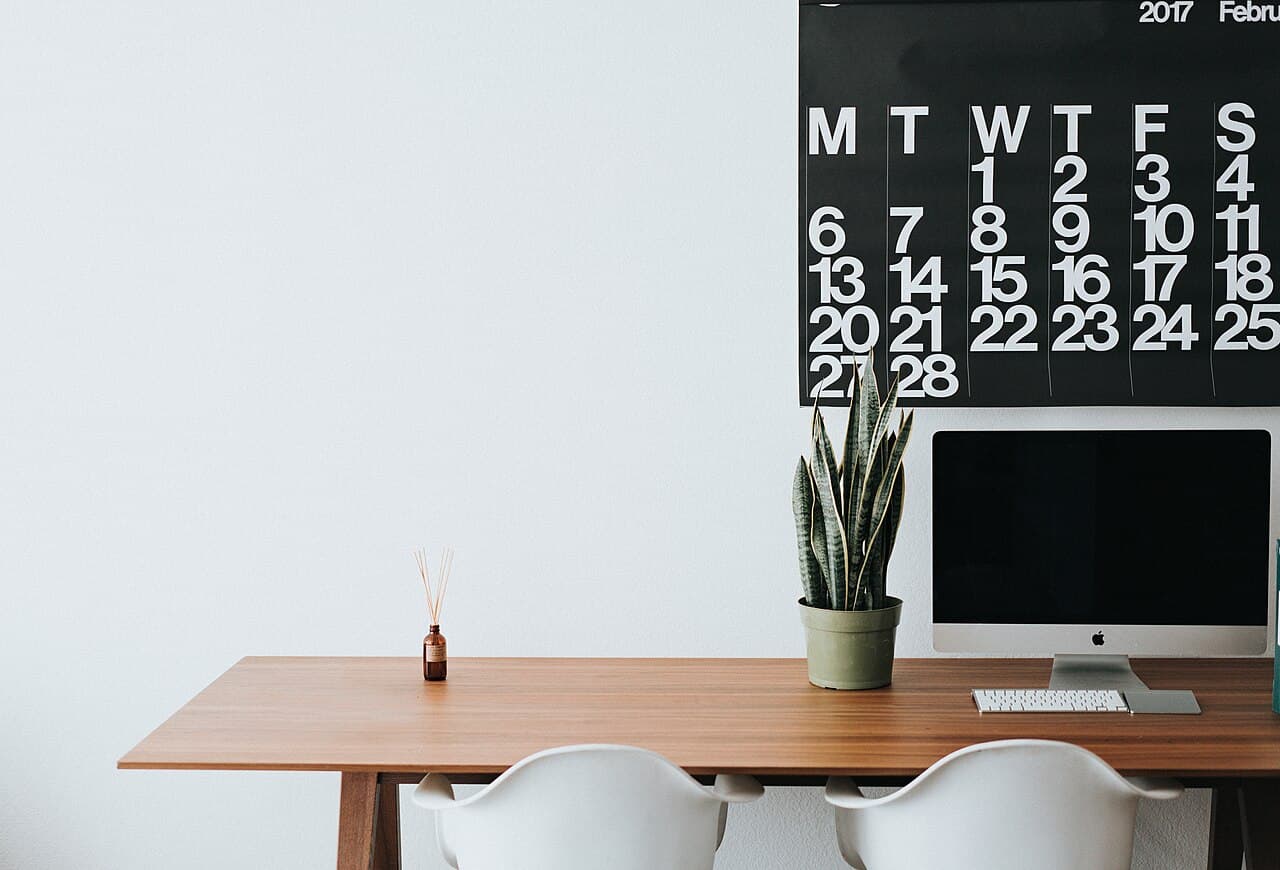 Mesa de trabajo minimalista con madera, planta y calendario